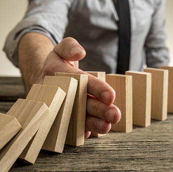 Man stopping domino effect on wooden table  Business success concept  Copy space 