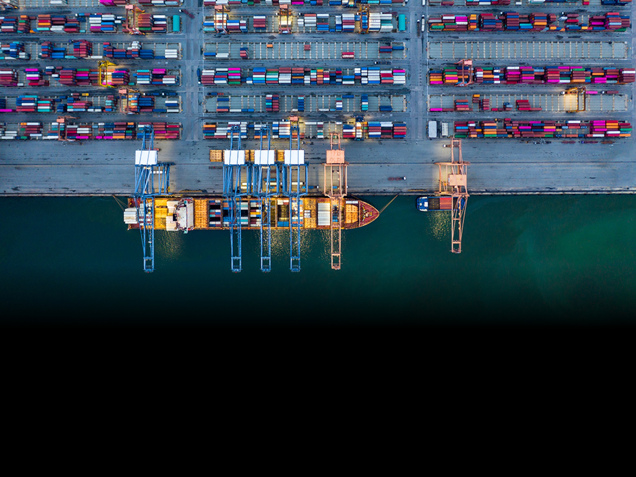 Aerial view container ship loaded in container terminal at night, Global business import export logistic and transportation, Commercial dock company cargo vessel freight shipping at night.