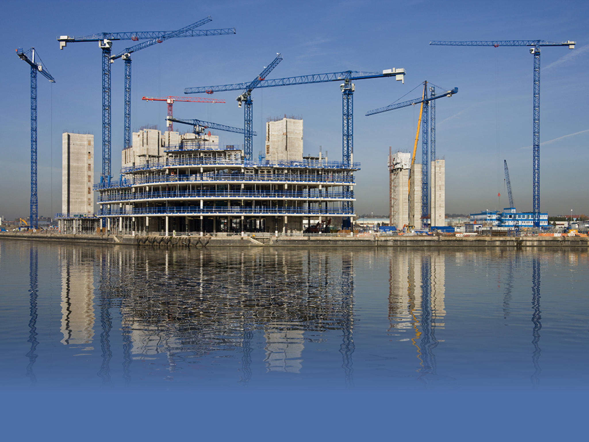Construction cranes building a waterside office development (In Salford Quays in Greater Manchester in Great Britain)