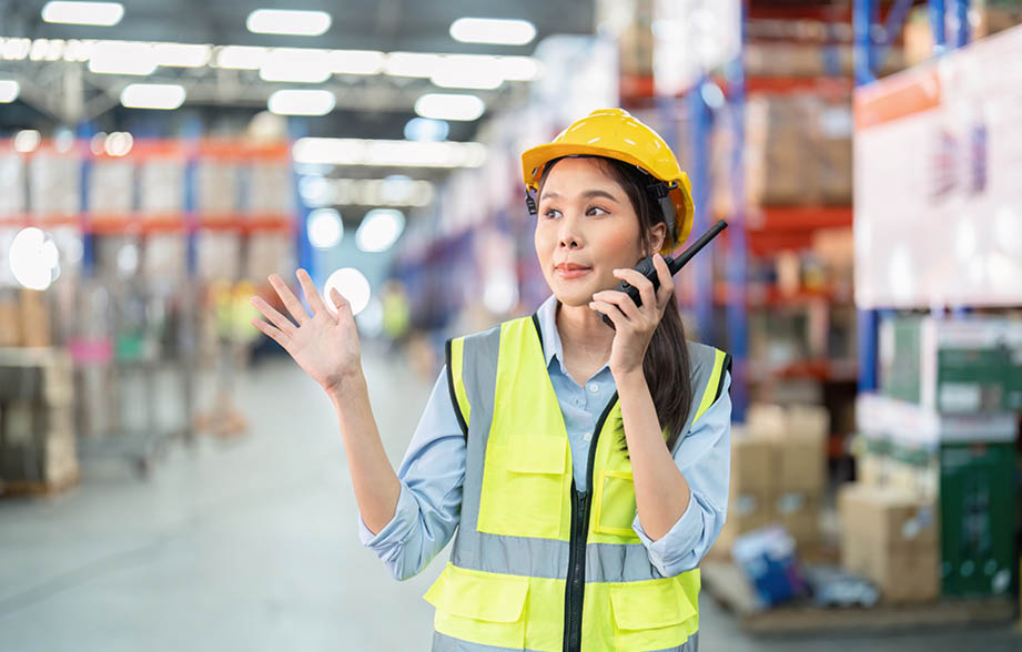 Staff in large storage warehouse use radio walkie talkie explain material storage location to team