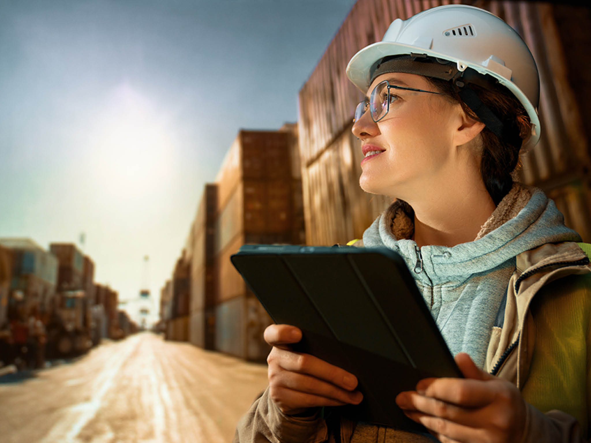 Female industrial engineer in white hard hat is working in container terminal.